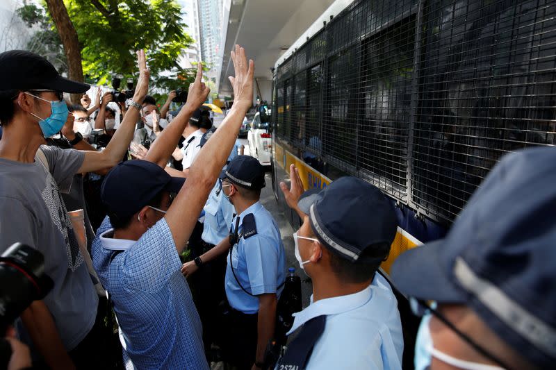 Supporters of Tong Ying-kit, the first person charged under the new national security law, greet a prison van outside West Kowloon Magistrates' Courts in Hong Kong