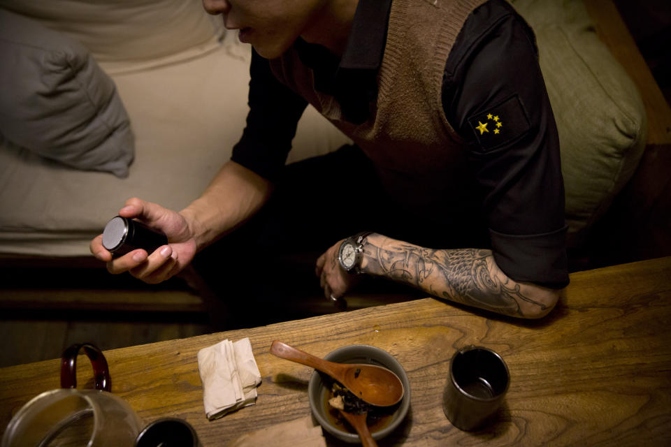 In this March 27, 2019, photo, Yin Hao, who also goes by Yin Qiang, holds a container of Tylox pills while sitting in a restaurant in Xi'an, northwestern China's Shaanxi Province. Officially, pain pill abuse is an American problem, not a Chinese one. But people in China have fallen into opioid abuse the same way many Americans did, through a doctor's prescription. And despite China's strict regulations, online trafficking networks, which facilitated the spread of opioids in the U.S., also exist in China. (AP Photo/Mark Schiefelbein)