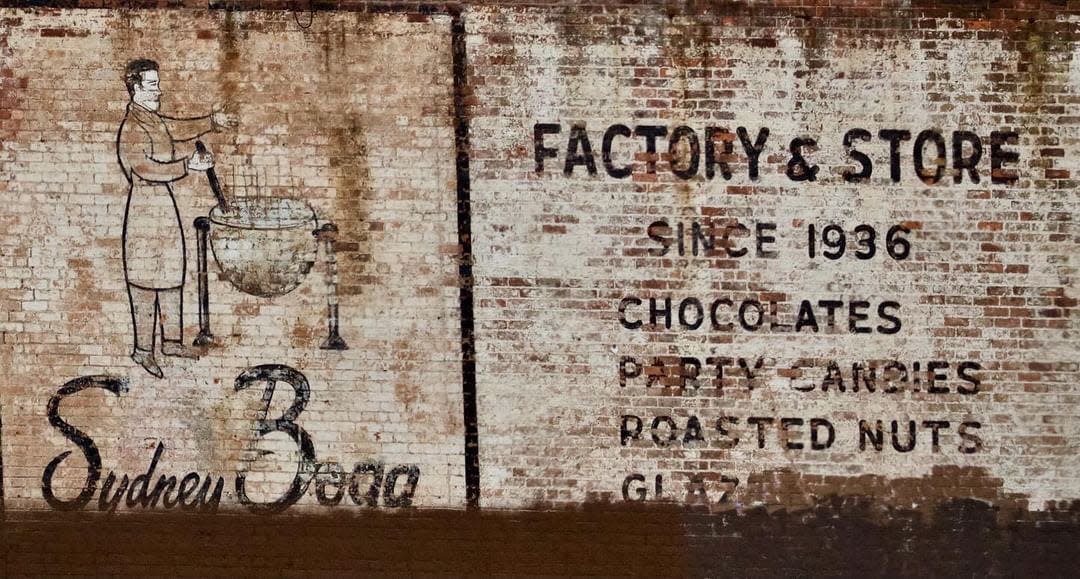 A ghost sign for Sydney Bogg's Factory & Store at 18932 Woodward Avenue across from Dutch Girl Donuts was preserved by an overlaying mural in 2021.
