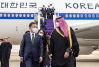 In this photo released by the Saudi Royal Palace, Saudi Crown Prince Mohammed bin Salman, right, receives South Korean President Moon Jae-in, at Riyadh international airport, Saudi Arabia, Tuesday, Jan. 18, 2022. It is the latest visit by a head of state to Saudi Arabia as a growing number of world leaders resume bilateral meetings and trips abroad following COVID-19 vaccine rollouts in many parts of the world. (Bandar Aljaloud/Saudi Royal Palace via AP)