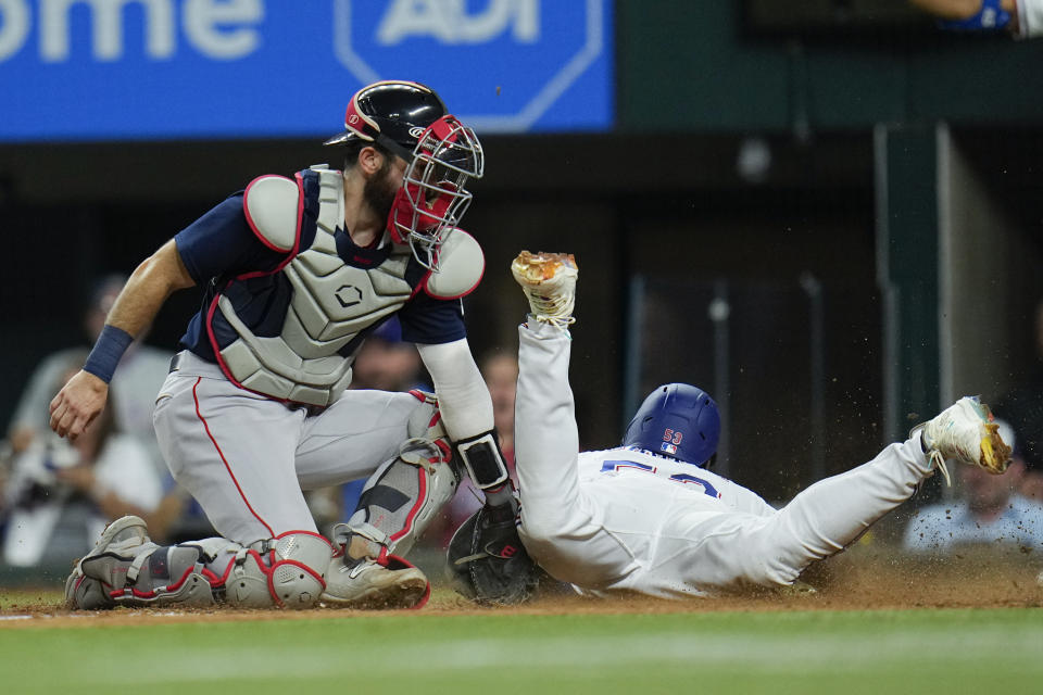 Texas Rangers' Adolis Garcia, right, slides in ahead of the tag by Boston Red Sox catcher Connor Wong on an RBI double by Jonah Heim during the sixth inning of a baseball game, Tuesday, Sept. 19, 2023, in Arlington, Texas. (AP Photo/Julio Cortez)