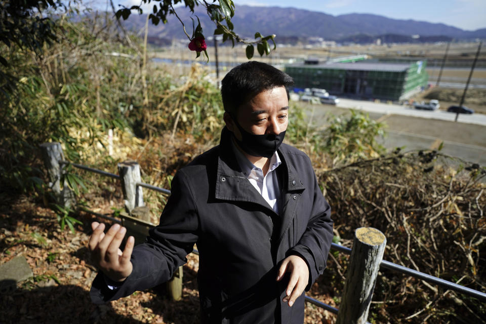 Michihiro Kono, president of Yagisawa Shoten Co., stands at a hill overlooking a newly built factory where his company's headquarters was located before the 2011 tsunami, Friday, March 5, 2021, in Rikuzentakata, Iwate Prefecture, northern Japan. Just a month after the tsunami as high as 17 meters (55 feet) smashed into the city of Rikuzentakata, soy sauce maker Kono inherited his family's two-century-old business from his father. Later this year the ninth generation owner of Yagisawa Shoten Co. will open a new factory on the same ground where his family started making soy sauce in 1807. (AP Photo/Eugene Hoshiko)