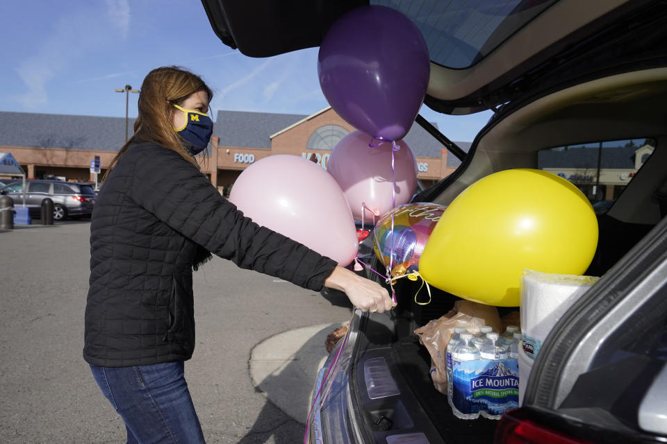 Volunteer Erica Stowe packs groceries and balloons into her vehicle, Thursday, Nov. 19, 2020, in Ann Arbor, Mich. A group of parents has come together to help support University of Michigan students while they are sick or quarantining. The group of mostly moms was started and is organized by Sherry Levine of Rye Brook, New York, who's also a mother of a Michigan student. After she spread the word on parent pages on Facebook, local volunteers stepped up to help fulfill student requests by dropping off groceries or supplies. (AP Photo/Carlos Osorio)