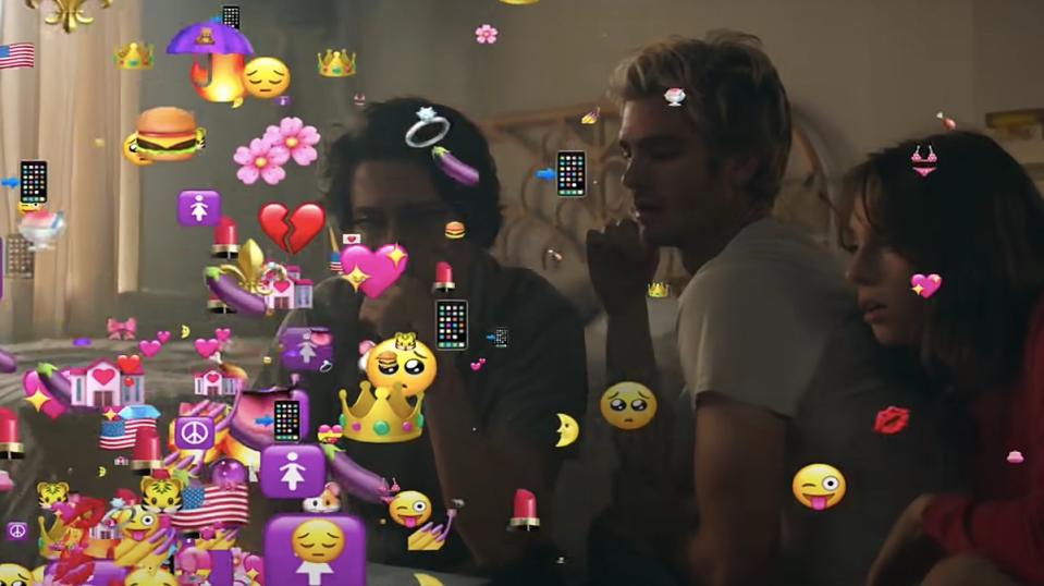 Nat Wolff, Andrew Garfield, and Maya Hawke look at a screen exploding with emojis in a scene from Mainstream.