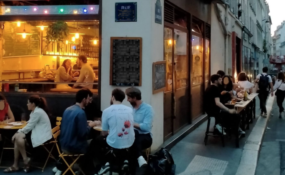 巴黎餐廳沿著店家外圍擺設的黃色鐵桌椅，還有由車阻改造的位子（照片右方的小木桌和高腳椅）。圖／Eva　提供