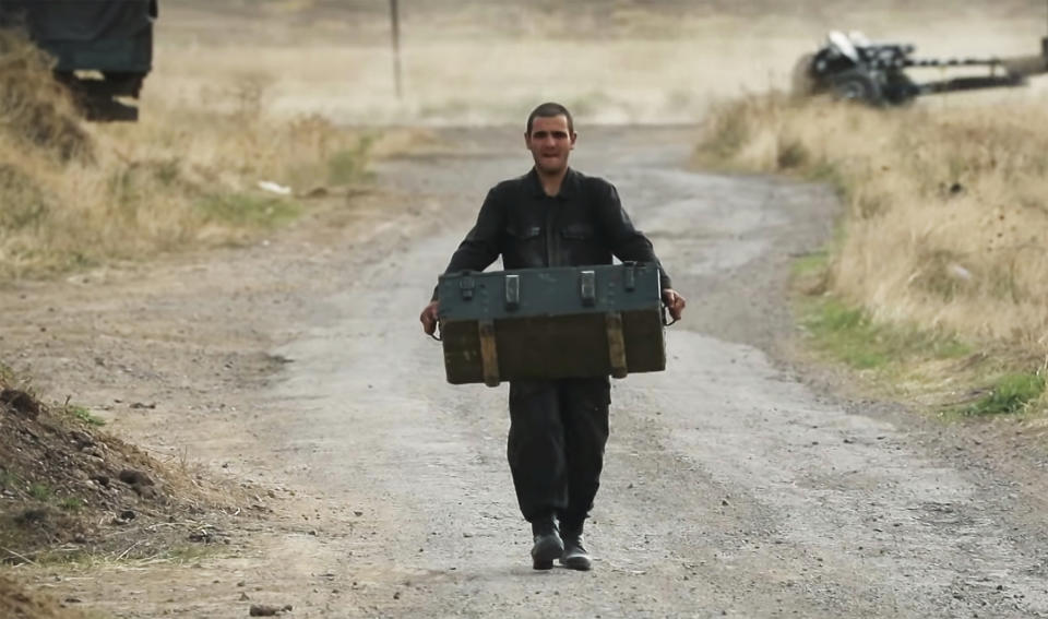 In this image taken from video released by Armenian Defense Ministry on Monday, Oct. 5, 2020, anArmenian soldier carries a box of ammunition at the contact line of the self-proclaimed Republic of Nagorno-Karabakh, Azerbaijan. Armenian military officials on Monday reported missile strikes hitting Stepanakert, the capital of Nagorno-Karabakh. The region lies in Azerbaijan but has been under the control of ethnic Armenian forces backed by Armenia since 1994. (Armenian Defense Ministry via AP)