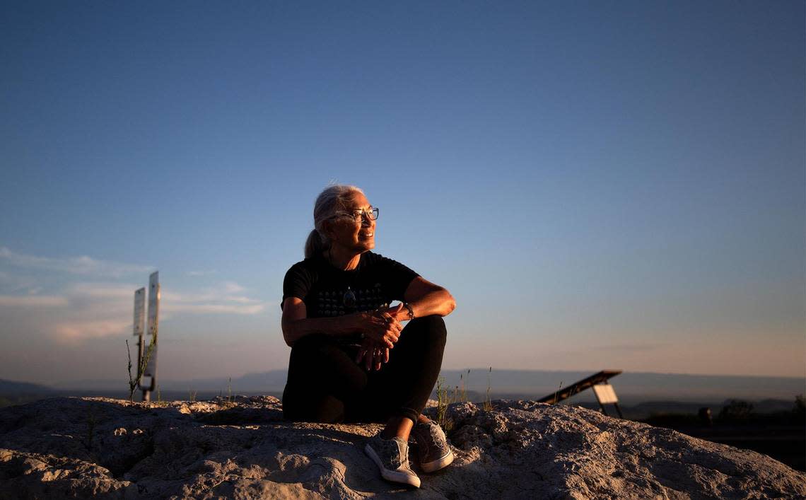 Patricia Golden, the caretaker of the Clark Hotel Museum in Van Horn, sits atop a boulder at a roadside rest stop in the Guadalupe Mountains, looking out over the peaks and valleys as the sun sets in August 2021. Golden moved to Van Horn, a town of less than 2,000 people, years ago because of the freedom she felt in the mountainous landscape that surround it.