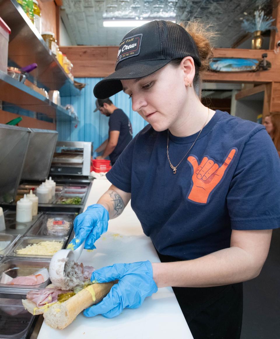 Samantha Yerger prepares a Key West Cubano sandwich at Deli Dudes within the Grab-a-Bite Food Court & Bar at 5260 Gulf Breeze Parkway on Friday, Jan. 26, 2024.