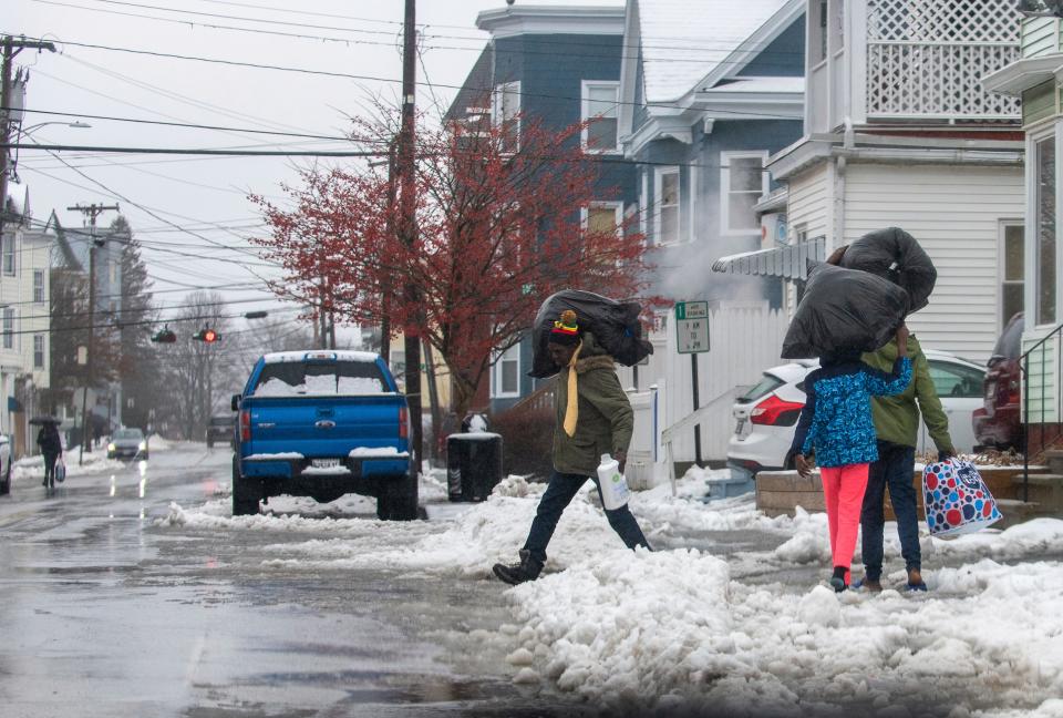 A family carries bundles of clean laundry through snow and puddles Saturday morning, Jan. 13, 2024, in downtown Lewiston, Maine, after visiting a neighborhood laundromat during a downpour. (Russ Dillingham/Sun Journal via AP) ORG XMIT: MELEE102