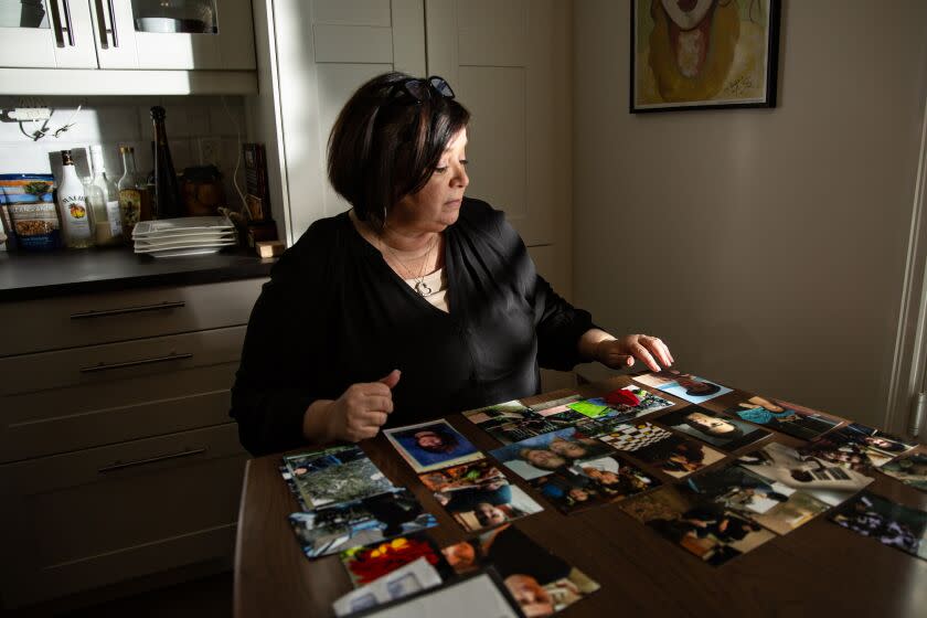 DUARTE, CA - DECEMBER 08: Deborah Smith sets at her dinning room table looking over photos of son Nicholas who is struggling with mental illness on Thursday, Dec. 8, 2022 in Duarte, CA. Deborah Smith has been struggling for more than a decade to get appropriate mental health care for her son, Nicholas, who has had eight short-term, mental health commitments but has not been placed in a conservatorship despite her pleading. (Jason Armond / Los Angeles Times)