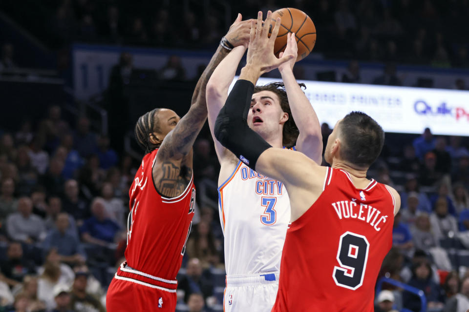 Oklahoma City Thunder guard Josh Giddey (3) prepares to shoot the ball as Chicago Bulls forward DeMar DeRozan, left, and center Nikola Vucevic (9) defend during the first half of an NBA basketball game, Wednesday, Nov. 22, 2023, in Oklahoma City. (AP Photo/Nate Billings)