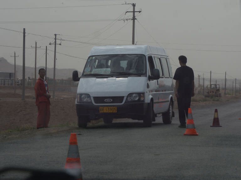 Chinese policemen guard a roadblock leading into the riot affected town of Lukqun, Xinjiang Province, on June 27, 2013. Armed police in China's ethnically divided Xinjiang have blocked the road to the site of riots that killed 27 people a day earlier in the region's deadliest violence in years, which state media called a "terrorist incident"