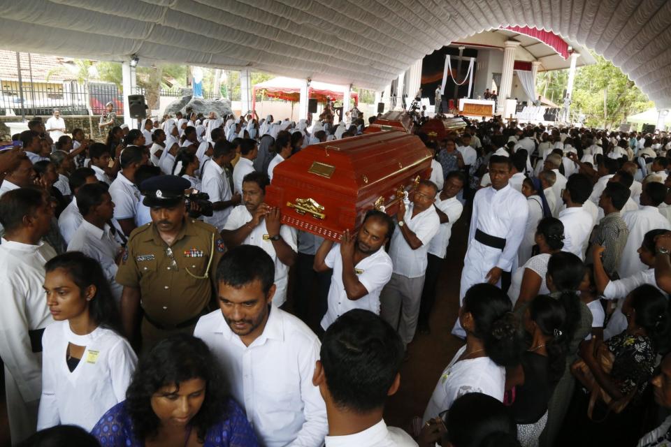 Coffins are carried to the graves during the mass funeral of the victims as Sri Lanka holds a day of mourning. (EPA)