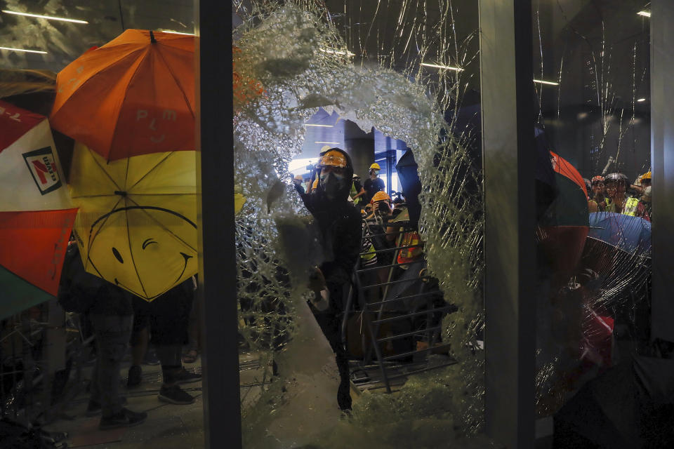 In this file photo taken Monday, July 1, 2019, a protester breaks the glass wall to enter the Legislative Council in Hong Kong, Protesters in Hong Kong took over the legislature's main building Monday night, tearing down portraits of legislative leaders and spray painting pro-democracy slogans on the walls of the main chamber. (AP Photo/Kin Cheung, File)