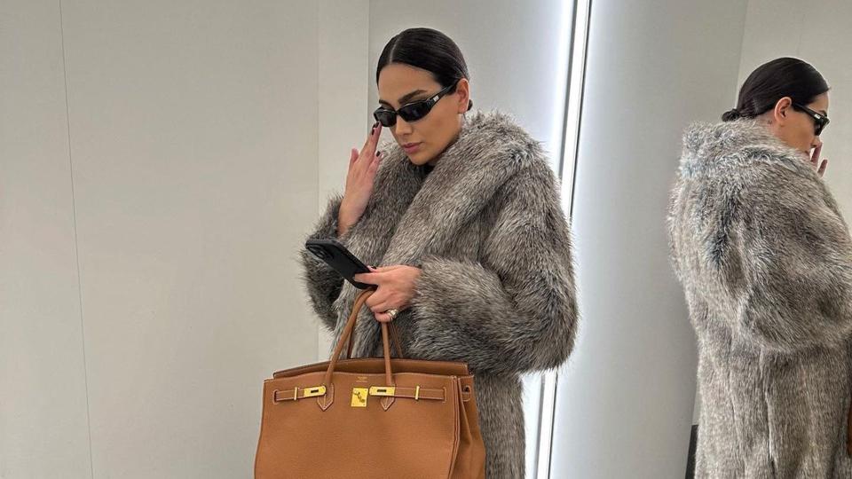 Style influencer @charlotteemilysanders wears a long fur coat, black sunglasses and a birking bag 