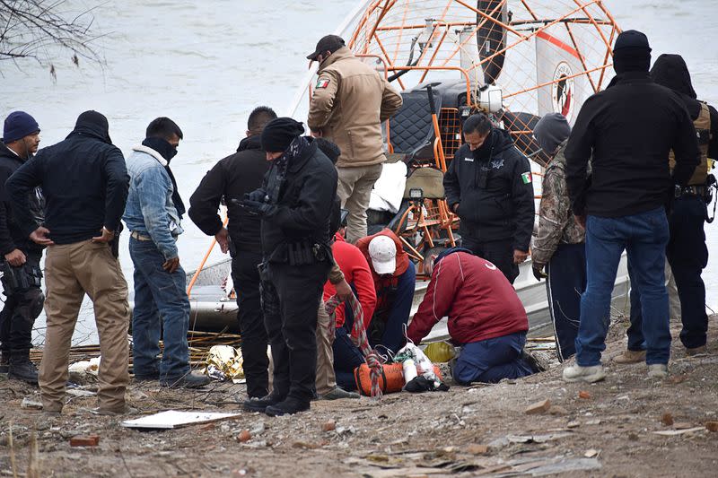 FILE PHOTO: Paramedics check the body of a Honduran migrant child, who drowned while crossing the frigid waters of the Rio Grande river from Mexico into the U.S. with his mother and sister, according to local media, in Piedras Negras