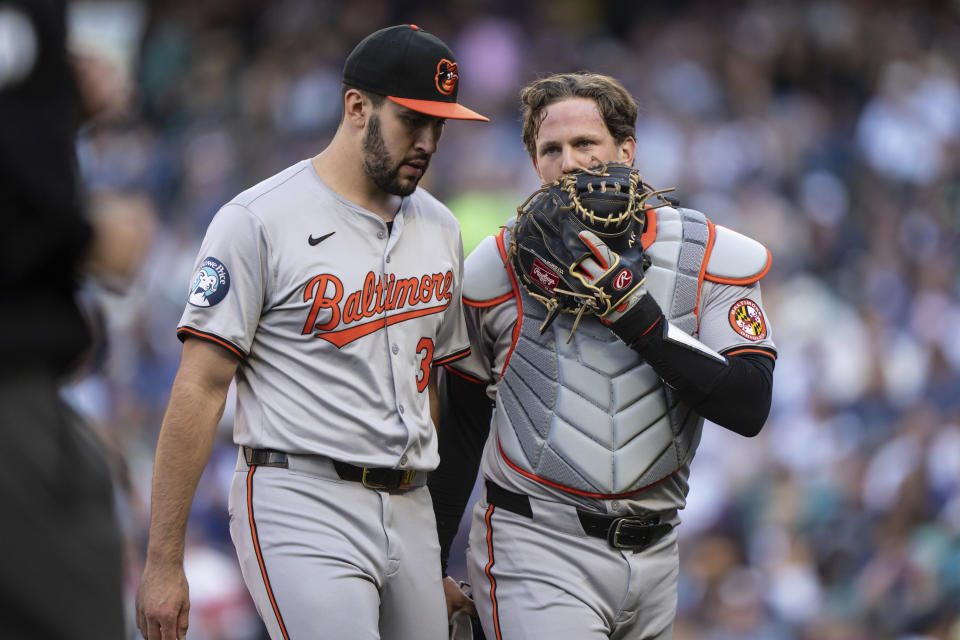 Baltimore Orioles starting pitcher Grayson Rodriguez, left, and catcher Adley Rutschman walk off the field at the end of the first inning of a baseball game against the Seattle Mariners, Tuesday, July 2, 2024, in Seattle. (AP Photo/Stephen Brashear)