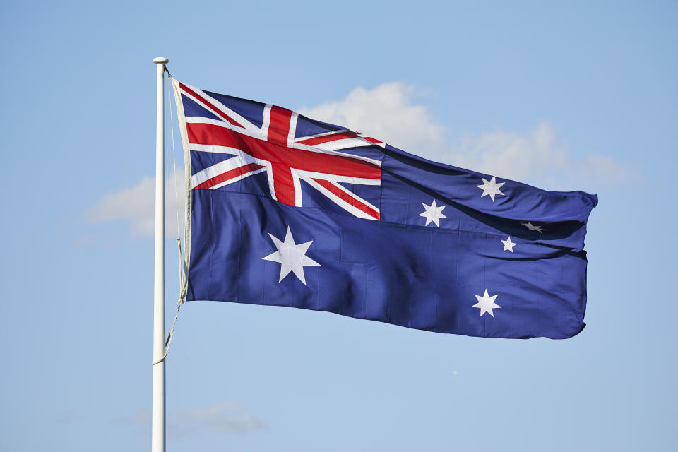 Flag of Australia on flagpole with a white cloud behind the flag