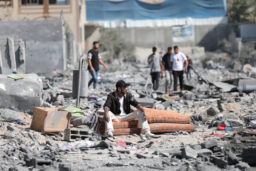 Palestinians walk by the buildings destroyed in the Israeli bombardment on al-Zahra, on the outskirts of Gaza City, Friday, Oct. 20, 2023. (AP Photo/Ali Mahmoud)