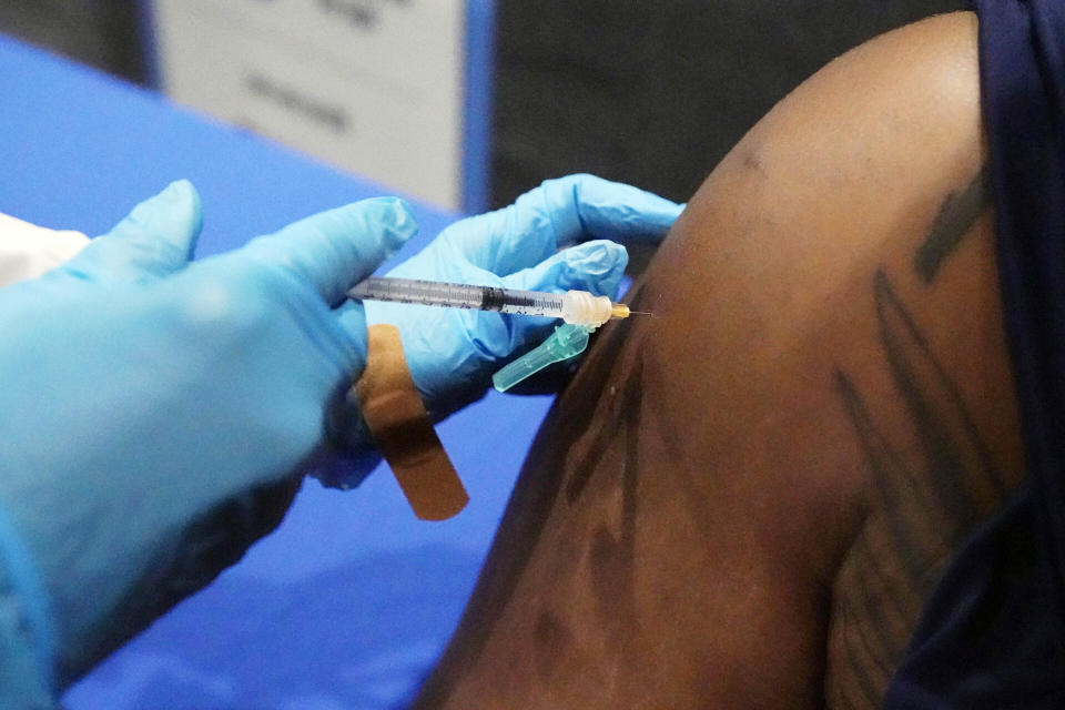 FILE - In this July 27, 2021, file photo, Timontre Graham, 21, a senior at Jackson State University and defensive lineman with the school's football team, receives his COVID-19 vaccination at the Rose E. McCoy Auditorium on the Jackson State University campus in Jackson, Miss. Several months since COVID-19 vaccinations were made widely available in the U.S., the subject continues to disrupt professional and college sports. ( AP Photo/Rogelio V. Solis, File)