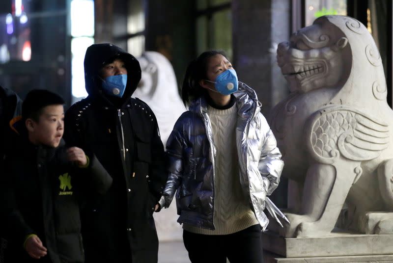 People wearing masks walk along a street in Beijing