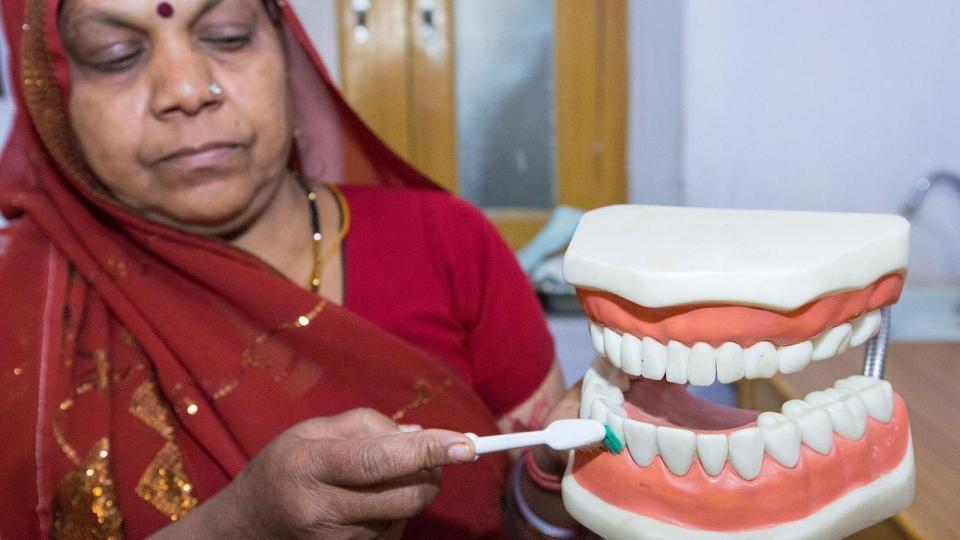 Una profesional dental demuestra cómo angular el cepillo contra los dientes