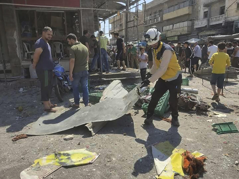 This photo provided by the Syrian Civil Defense White Helmets, which has been authenticated based on its contents and other AP reporting, shows a Syrian White Helmet civil defense worker, center, works at the rocket attacked scene, at al-Bab town, north Syria, Friday, Aug. 19, 2022. A rocket attack on a crowded market in a town held by Turkey-backed opposition fighters in northern Syria Friday killed several people and wounded dozens, an opposition war monitor and a paramedic group reported. (Syrian Civil Defense White Helmets via AP)