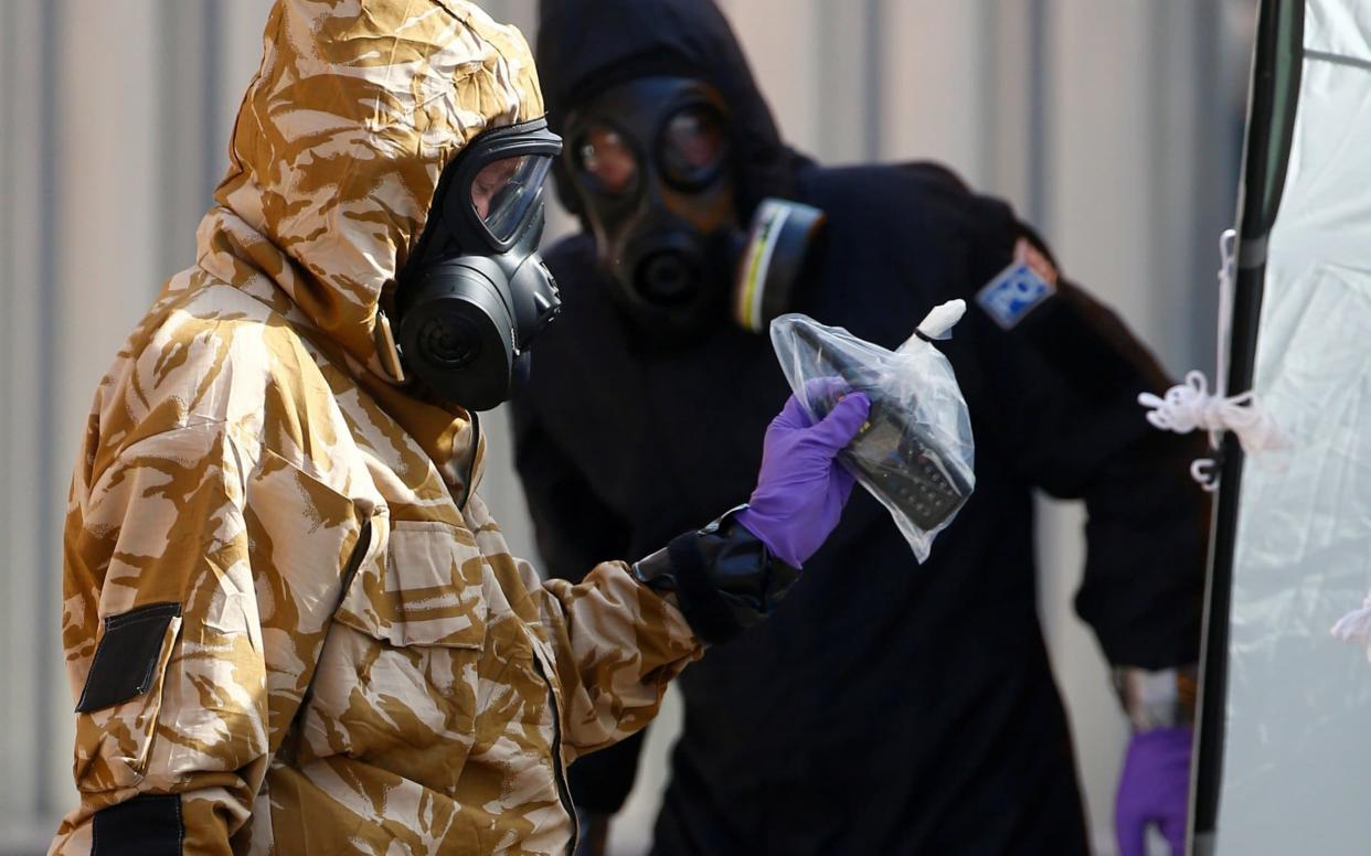 Forensic investigators, wearing protective suits, emerge from the rear of John Baker House, the home of Novichok victim Dawn Sturgess - REUTERS