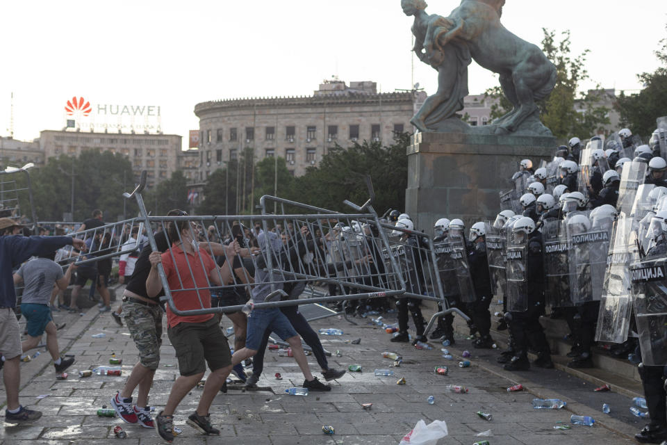 Protesters throw barricades at riot police in Belgrade, Serbia, Wednesday, July 8, 2020. Police have fired tear gas at protesters in Serbia's capital during the second day of demonstrations against the president's handling of the country's coronavirus outbreak. President Aleksandar Vucic backtracked on his plans to reinstate a coronavirus lockdown in Belgrade this week, but it didn't stop people from firing flares and throwing stones while trying to storm the downtown parliament building. (AP Photo/Marko Drobnjakovic)