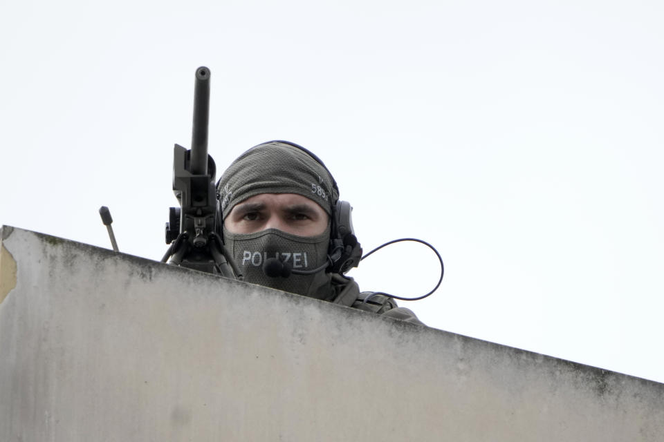 A police sharp shooter stands atop a building overlooking the Brandenburg Gate in Berlin, waiting for the arrival of Britain's King Charles III and Camilla, the Queen Consort, Wednesday, March 29, 2023. King Charles III arrived Wednesday for a three-day official visit to Germany. (AP Photo/Markus Schreiber)