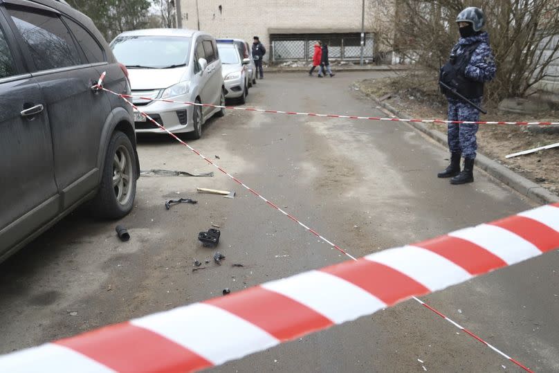 Ein Polizist bewacht einen Bereich mit den Trümmern einer Drohne in der Nähe eines beschädigten Wohnhauses in St. Petersburg, 2. März 2024