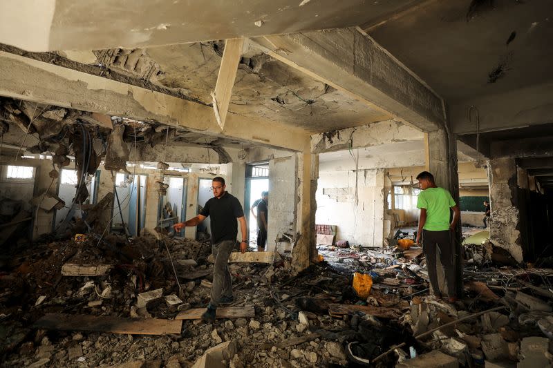 Palestinians inspect a school after it was hit by an Israeli strike, in Gaza City