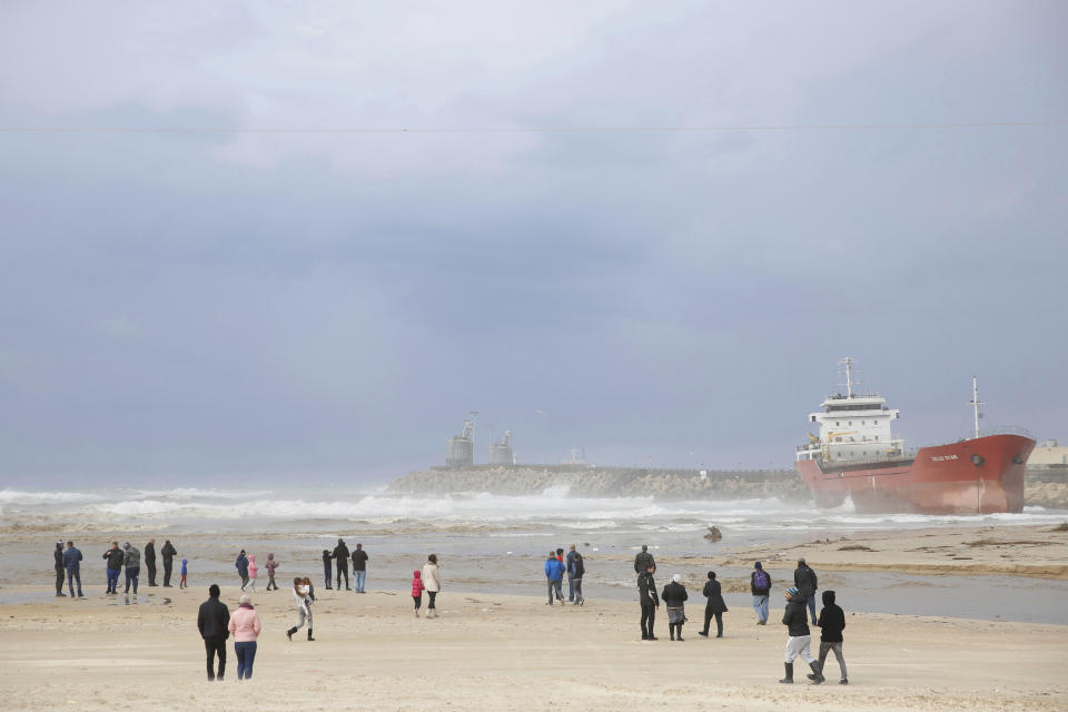 People look at the Zelek Star cargo ship carrying cement, stranded in the Mediterranean Sea beach in the southern Israeli port city of Ashdod, Friday, Dec. 27, 2019. Strong winds and waves forced the vessel away from its anchor point near the port of Ashdod on Thursday. (AP Photo/Ariel Schalit)