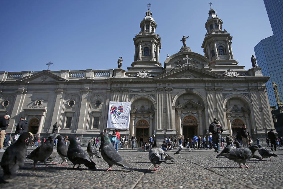 FILE - In this May 18, 2018 file photo, pigeons are fed in front of the Santiago Cathedral, in Santiago, Chile. Pope Francis' high-stakes sex abuse prevention summit is meant to call attention to the crisis as a global problem that requires a global response. Francis discovered first-hand just how pervasive clerical sex abuse is — and how effectively it has been covered up by the Catholic hierarchy — when in January 2018 he branded as "calumny" accusations of cover-up against a Chilean bishop he had strongly defended. (AP Photo/Luis Hidalgo, file)