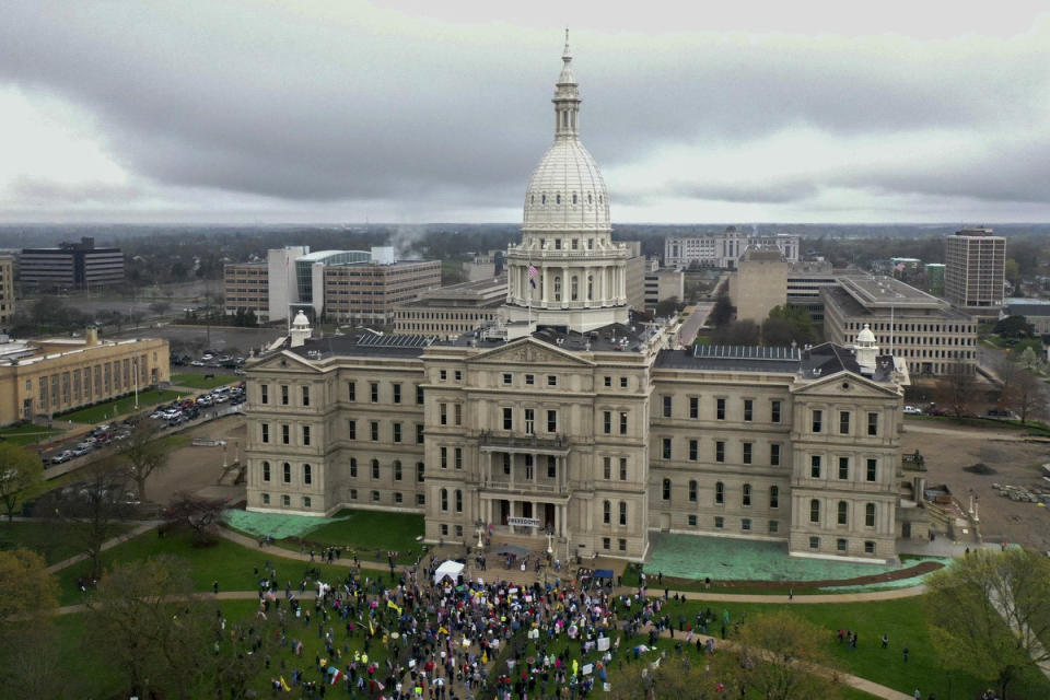 Protesters congregate at the Capitol in Lansing, Mich., Thursday April 30, 2020. The Republican-led Michigan Legislature refused Thursday to extend the state's coronavirus emergency declaration and voted to authorize a lawsuit challenging Democratic Gov. Gretchen Whitmer's authority and actions to combat the pandemic. The step came as hundreds of conservative activists, including some who were openly carrying rifles, returned to the Capitol to denounce her stay-at-home order. (Neil Blake/The Grand Rapids Press via AP)