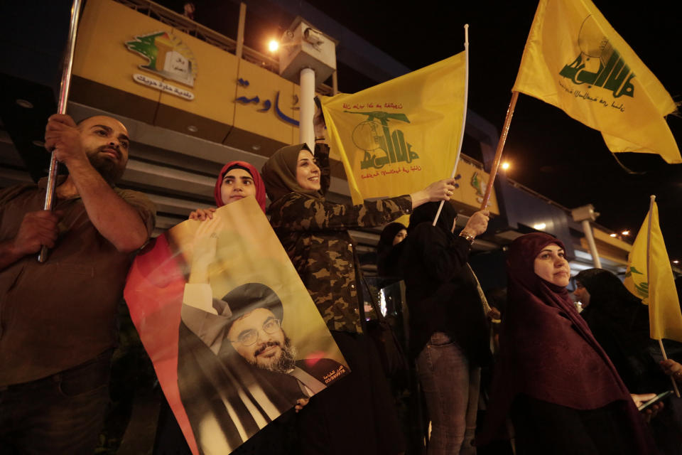 FILE - In this Oct. 25, 2019 file photo, supporters of Hezbollah leader Sayyed Hassan Nasrallah hold his pictures and waves Hezbollah flags in the southern suburb of Beirut, Lebanon. Iranian-backed Hezbollah built a reputation among supporters in Lebanon as a champion of the poor and a defender of the country against Israel's much more powerful military. Lebanon’s protests have shown unusual overt anger at the country’s powerhouse, Hezbollah. (AP Photo/Hassan Ammar, File)