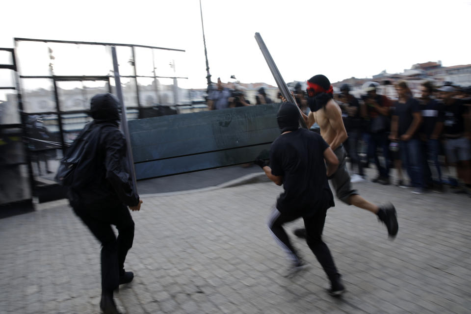 Protestors throw a road sign at a police barricade in Bayonne, France, Saturday, Aug. 24, 2019. World leaders and protesters are converging on the southern French resort town of Biarritz for the G-7 summit. President Donald Trump will join host French President Emmanuel Macron and the leaders of Britain, Germany, Japan, Canada and Italy for the annual summit in the nearby resort town of Biarritz. (AP Photo/Emilio Morenatti)