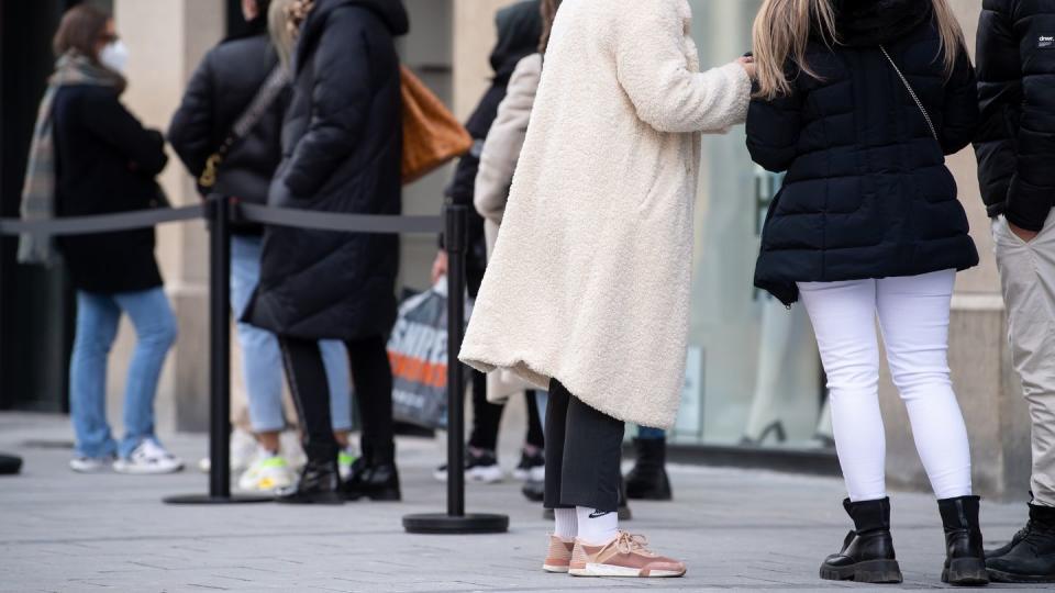 Menschen warten vor einem Geschäft in der Münchner Innenstadt auf Einlass. Die Wirtschaft reagiert erleichtert auf die Absage des Oster-Lockdowns.