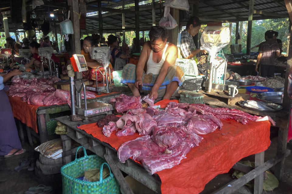 A pork vendor chops meat while waiting for customers at a wet market in Yangon, Myanmar on Nov. 12, 2021. The military takeover in Myanmar has set its economy back years, if not decades, as political unrest and violence disrupt banking, trade and livelihoods and millions slide deeper into poverty. (AP Photo)