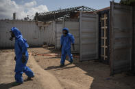 French emergency workers, part of a special unit working with chemicals, walk next to damaged containers near the site of last week's explosion, in the port of Beirut, Lebanon, Monday, Aug. 10, 2020. The unit is identifying potential leaks and securing an area where containers with flammable liquids have been damaged by the blast. (AP Photo/Felipe Dana)