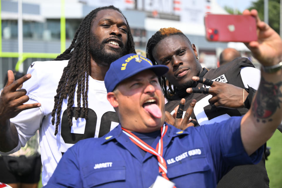 Cleveland Browns defensive end Jadeveon Clowney, back left, and tight end David Njoku pose with a member of the U.S. Coast Guard after the NFL football team's training camp ended for the day Wednesday, Aug. 3, 2022, in Berea, Ohio. (AP Photo/David Richard)