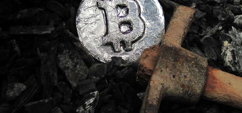 A pickaxe lies next to a rough silver coin marked with a B.