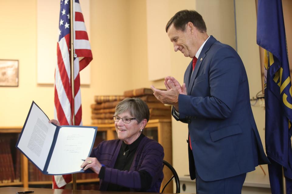 Sen. Dennis Pyle, R-Hiawatha, claps as Gov. Laura Kelly holds up the tax cut bill that she ceremonially signed on July 2 in Holton.