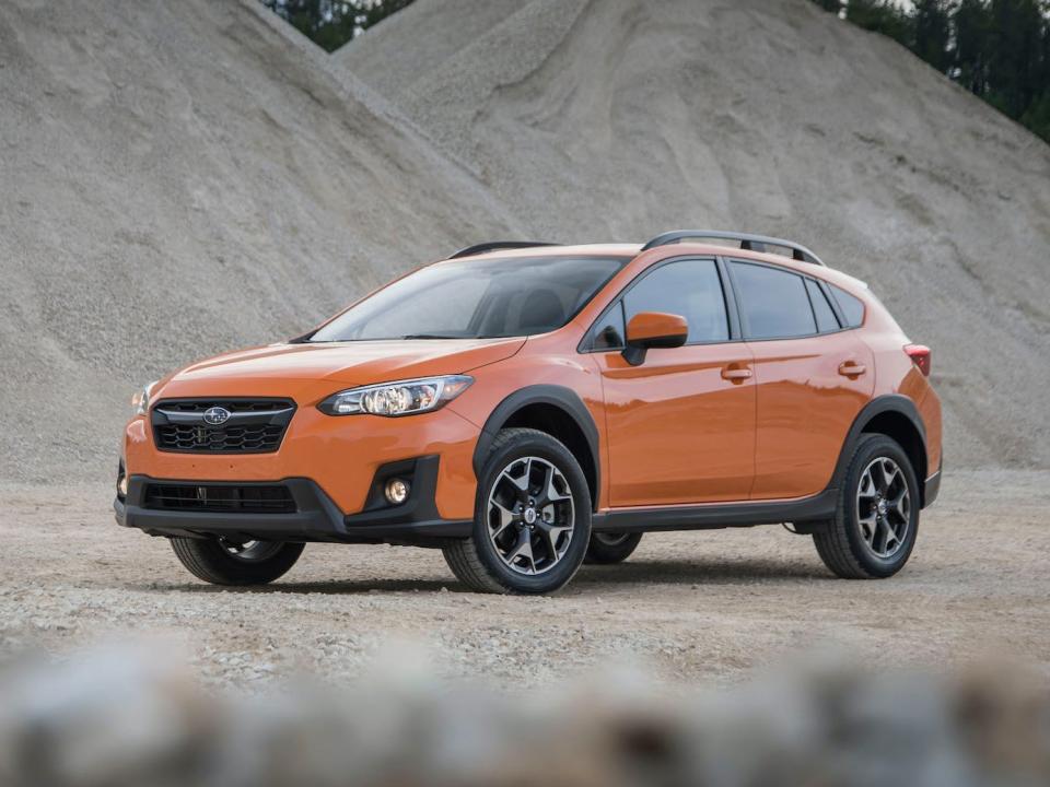 An orange 2020 Subaru Crosstrek Premium next to gray hills.