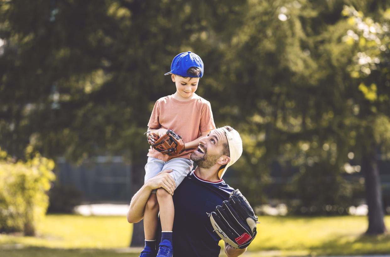 A Father and son playing baseball in sunny day at public park