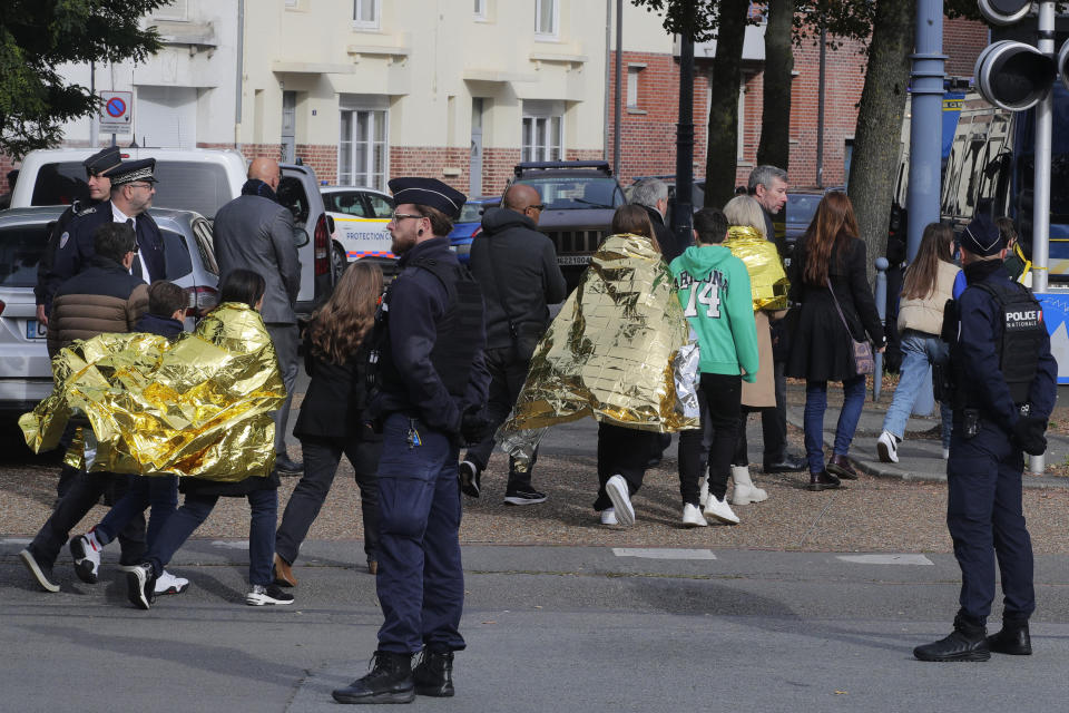 Police officers escort children outside the Gambetta high school during a bomb alert Monday, Oct. 16, 2023 in Arras, northern France. French authorities say the high school where a teacher was fatally stabbed in an attack last week has been evacuated over a bomb alert, as France's President cut short travel plans abroad to host a security meeting Monday.(AP Photo/Michel Spingler)
