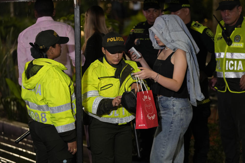 La policía revisa la edad de una mujer en la entrada del parque Lleras para impedir el acceso de menores en Medellín, Colombia, el viernes 2 de febrero de 2024. La Alcaldía impuso restricciones de paso a menores a esa zona en un intento por eliminar la explotación sexual. (AP Foto/Fernando Vergara)