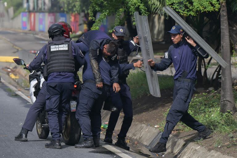 Agentes de policía cargan a un policía herido duarnte una protesta en Caracas.