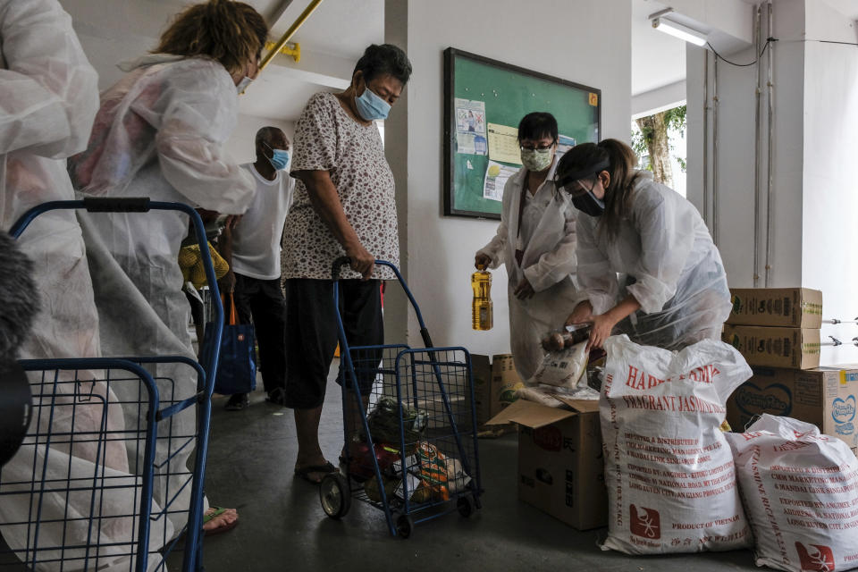Volunteers of Keeping Hope Alive prepare grocery items for a flat resident Sunday, Oct. 4, 2020 in Singapore. Members of the volunteer group conduct weekend door-to-door visits to deliver goods or provide services to people in need. (AP Photo/Ee Ming Toh)