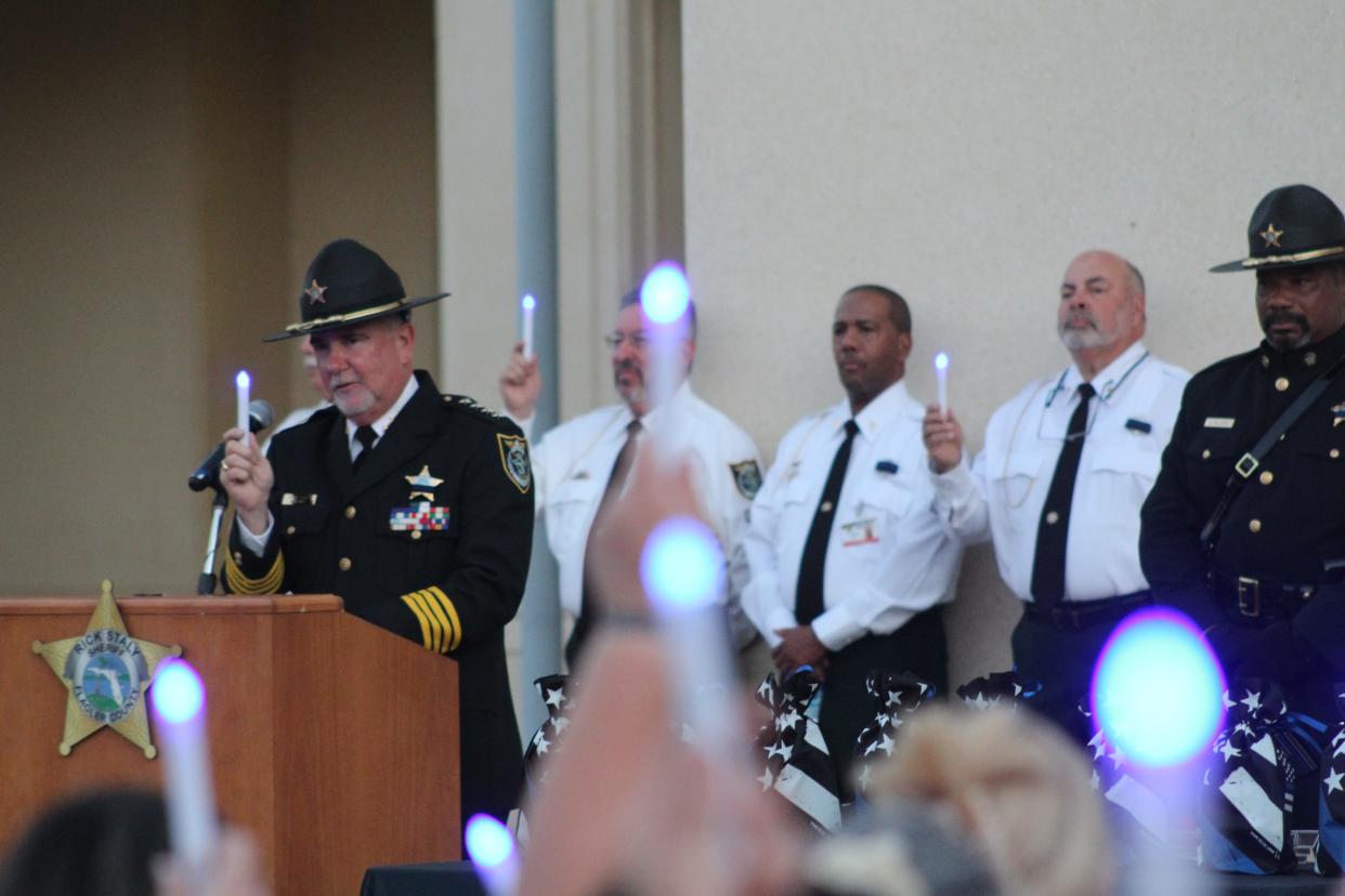 Flagler County Sheriff Rick Staly and the family and friends of fallen officers hold up electric blue candles during a memorial service on May 5, 2022, at the Kim C. Hammond Justice Center in Bunnell.